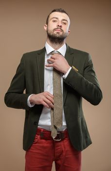 young man in a green suit and tie, beige background