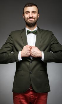happy young man in a green suit on a gray background