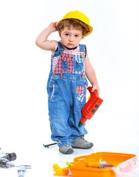 Little builder. Baby boy in a helmet plays in the builder with tools. Isolated over white.