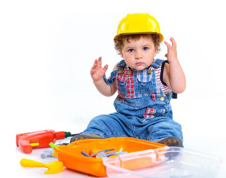 Little builder. Baby boy in a helmet plays in the builder with tools. Isolated over white.