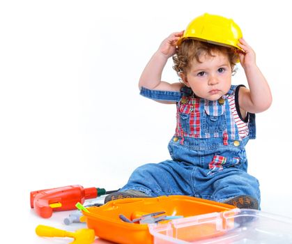 Little builder. Baby boy in a helmet plays in the builder with tools. Isolated over white.