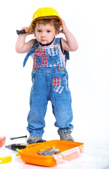 Little builder. Baby boy in a helmet plays in the builder with tools. Isolated over white.