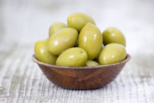 Bowl with fresh green olives on a rustic wooden tabletop