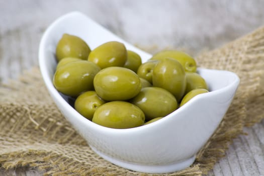 Bowl with fresh green olives on a rustic wooden tabletop