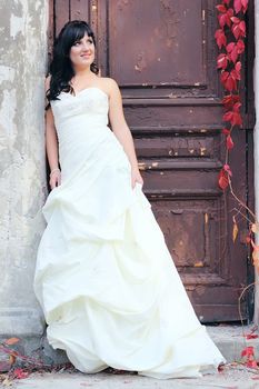 Young beautiful girl in the wedding dress near the door