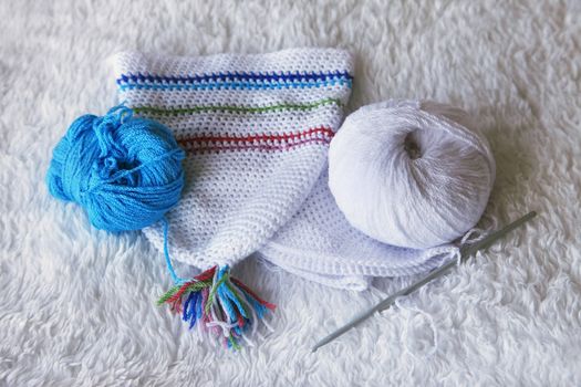 Baby hat from viscose and knitting hooks. Needlework accessories isolated on white background.