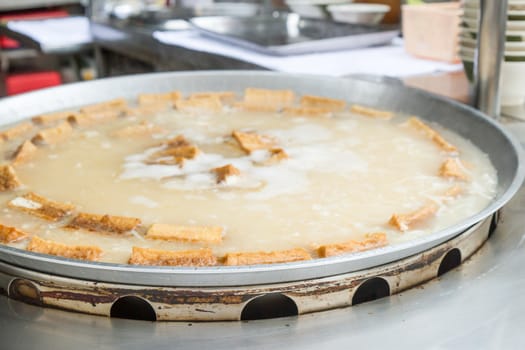 Big dish of tofu being boiled at a stall