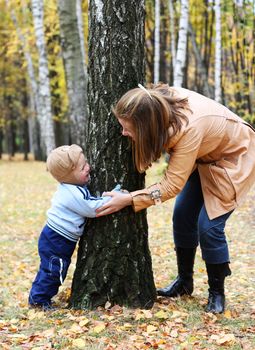 Mother with son play seek and hide in a park