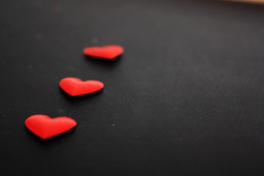 three red heart lying on a black background 