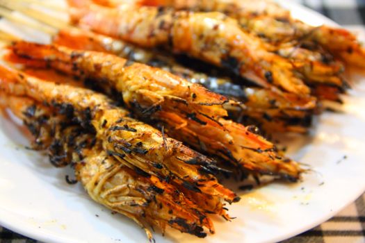 Plate of BBQ shrimp skewers on white plate