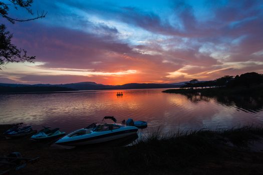 Dawn morning color reflections in sky clouds reflections on boats by dam lake waters