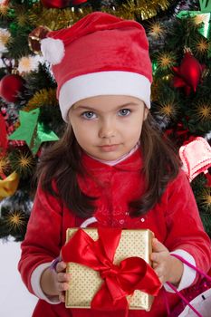 Cute girl in Santa hat holding Christmas gift