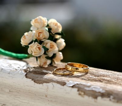 Bunch of white roses and the rings for just married on the wooden balustrade