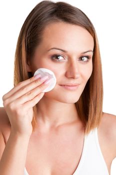 Woman removing make-up with a cotton pad in front of a mirror, isolated in white