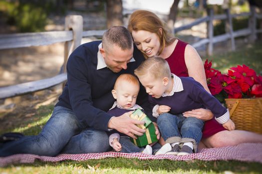 Beautiful Small Young Family Opening Christmas Gifts in the Park.