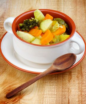 Homemade Rustic Vegetable Stew with Broccoli, Carrot, Leek and Potato in Beige Bowl with Wooden Spoon on Wooden background
