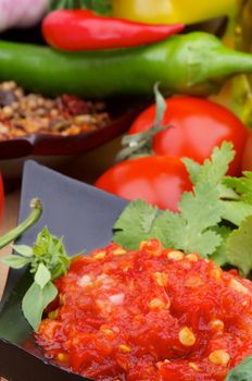 Arrangement of Bruschetta Sauce in Black Bowl on Ingredients, Spices and Greens background