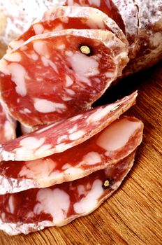 Slices of Delicious Raw Smoked Finocchiona with Peppercorn closeup on Wooden Cutting Board