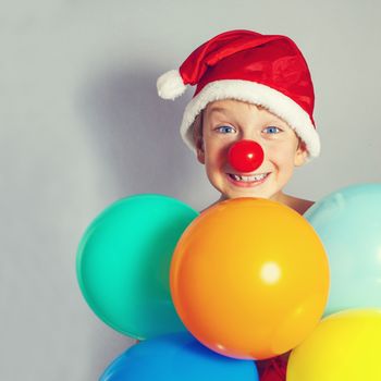 boy in Santa Claus hat holding balloons