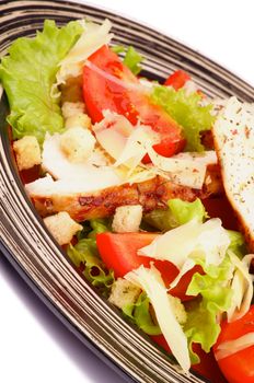 Caesar Salad with Grilled Chicken Breast, Garlic Crouton, Lettuce, Tomatoes and Grated Parmesan Cheese closeup on Striped Plate