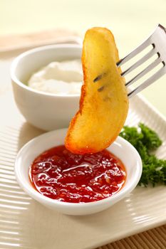 Dipping a potato wedge into sweet chili sauce with a fork.
