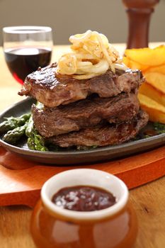 Grilled triple decker rib fillet steak with fried onion and chips ready to serve.