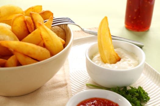 A crisp potato wedge dunked in a bowl of sour cream.