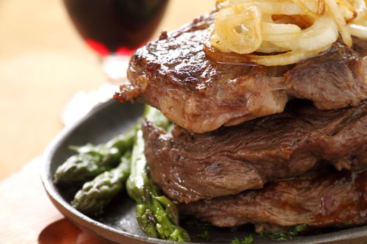 Fried onions on top of a stack of beef steaks.