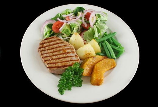 Hearty dinner of steak, vegetables and a side salad.