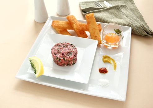 Steak tartare with raw egg in a glass ready to add to the beef.