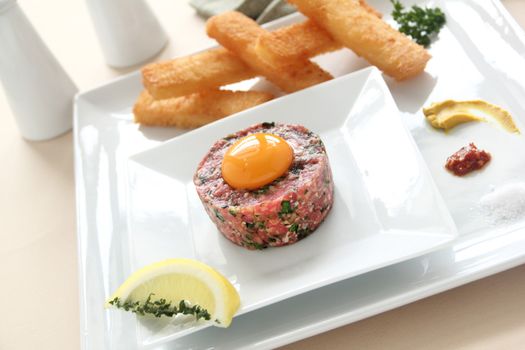 Delicious steak tartare with raw egg and condiments ready to serve.