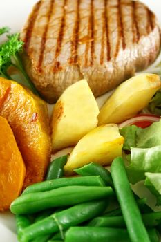 Hearty dinner of grilled steak, baked vegetables and a side salad.