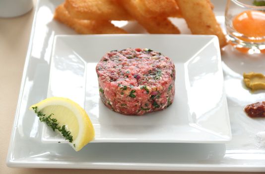 Steak tartare with raw egg in a glass ready to add to the beef.