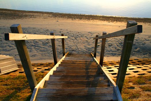 Old wooden stairs leading to the beach at daybreak.