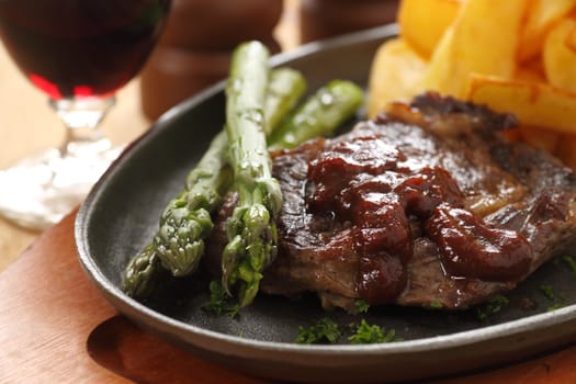 Grilled fillet steak with asparagus and barbeque sauce with potato wedges.