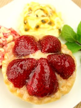 Strawberry custard tart with passionfruit cream and cranberry cream with a mint garnish.