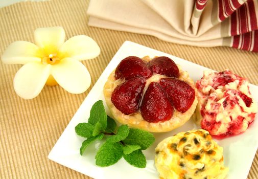 Strawberry custard tart with passionfruit cream and cranberry cream with a mint garnish.