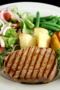 Hearty dinner of steak, vegetables and a side salad.