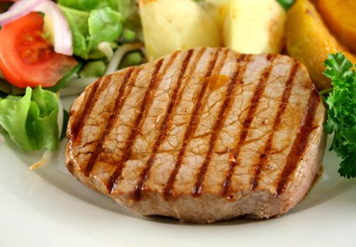 Hearty dinner of grilled steak, vegetables and a side salad.