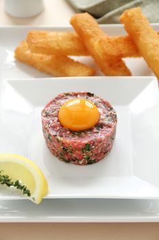 Delicious steak tartare with raw egg and condiments ready to serve.