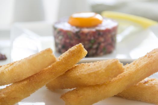 Delicious steak tartare with raw egg and fried bread strips ready to serve.