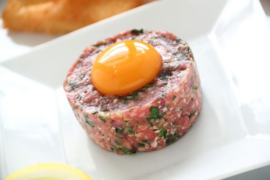 Delicious steak tartare with raw egg and condiments ready to serve.