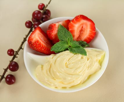 Delightful bowl of fresh strawberries and cream with a sprig of mint.