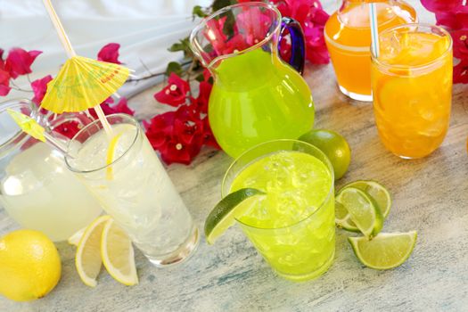 A selection of summer drinks with ice including lime, orange and lemon.