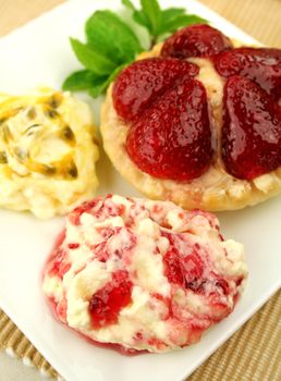 Strawberry custard tart with passionfruit cream and cranberry cream with a mint garnish.