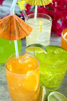 A selection of summer drinks with ice including lime, orange and lemon.