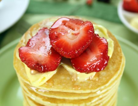 Delicious strawberry pancake stack stack dripping with honey with cream.