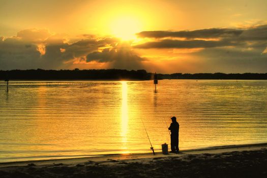 Fisherman on the beach at sunrise on a still morning.