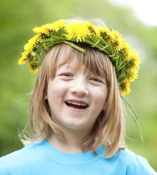 portrait of a boy with long blond hair wearing a flower wreath smiling