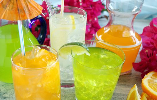 A selection of summer drinks with ice including lime, orange and lemon.